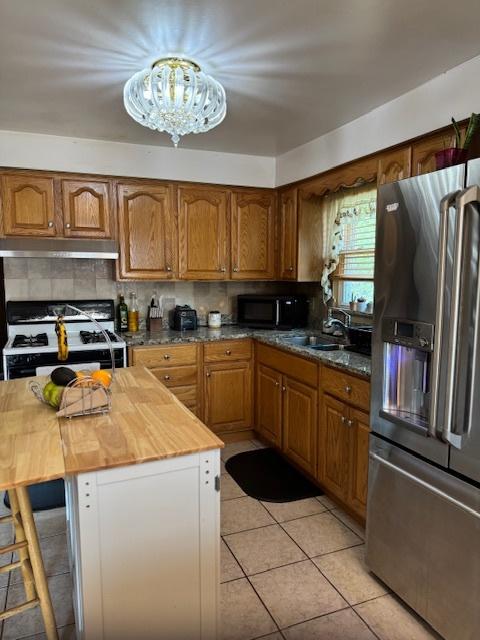 14240 S Manistee Ave, Burnham, IL 60633 - kitchen with stainless steel fridge with ice dispenser, wood counters, under cabinet range hood, a chandelier, and brown cabinetry