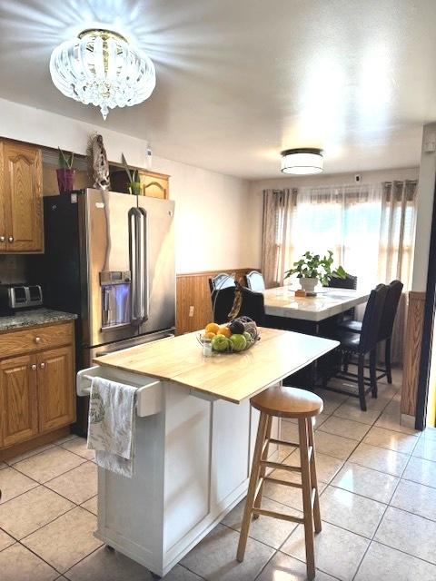 14240 S Manistee Ave, Burnham, IL 60633 - kitchen featuring light tile patterned floors, a wainscoted wall, stainless steel refrigerator with ice dispenser, butcher block counters, and brown cabinets