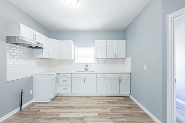 12452 S Eggleston Ave, Chicago, IL 60628 - kitchen featuring light wood-style flooring, under cabinet range hood, tasteful backsplash, white cabinets, and light countertops