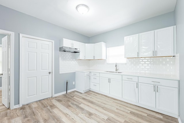 12452 S Eggleston Ave, Chicago, IL 60628 - kitchen featuring under cabinet range hood, light wood-type flooring, tasteful backsplash, white cabinetry, and light countertops