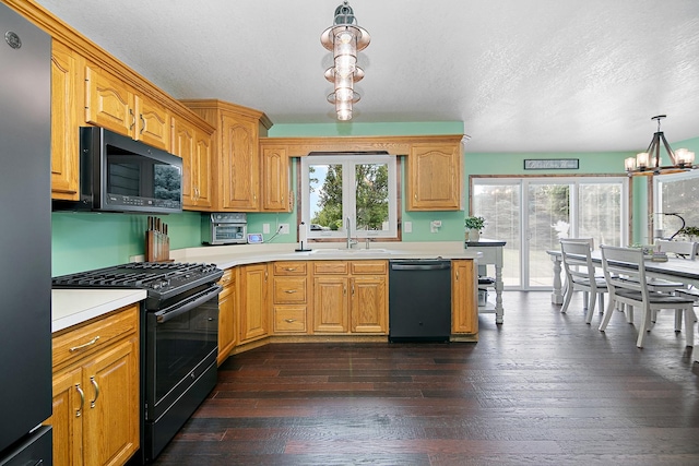 1553 Noble Quest Dr, Bourbonnais, IL 60914 - kitchen featuring black appliances, a chandelier, light countertops, dark wood-style flooring, and hanging light fixtures
