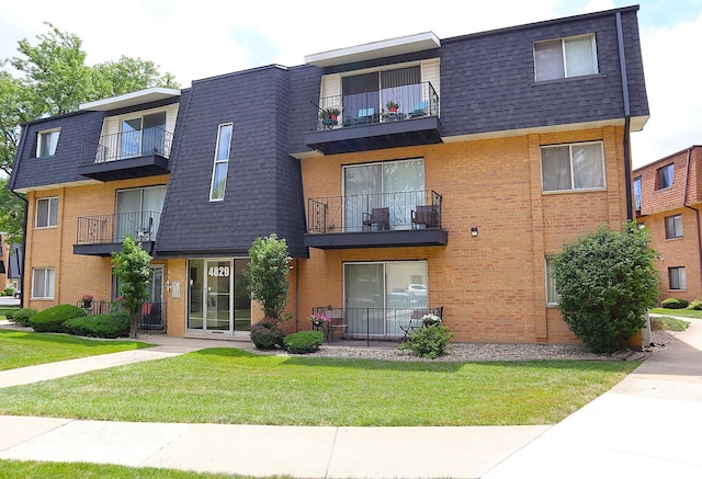 4829 W 109th St Unit 203, Oak Lawn, IL 60453 - view of front facade featuring mansard roof, brick siding, a balcony, and a front lawn