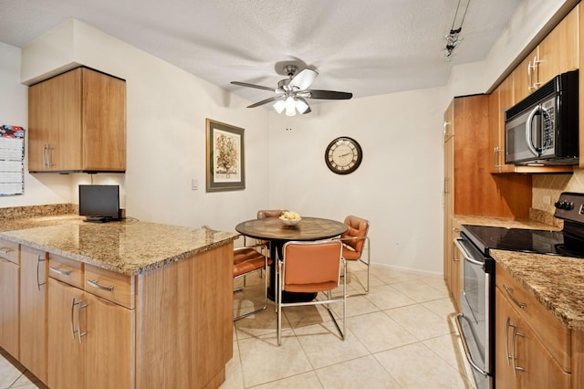 1671 Mission Hills Rd Unit 501, Northbrook, IL 60062 - kitchen with stainless steel range with electric cooktop, black microwave, a peninsula, a ceiling fan, and light stone countertops