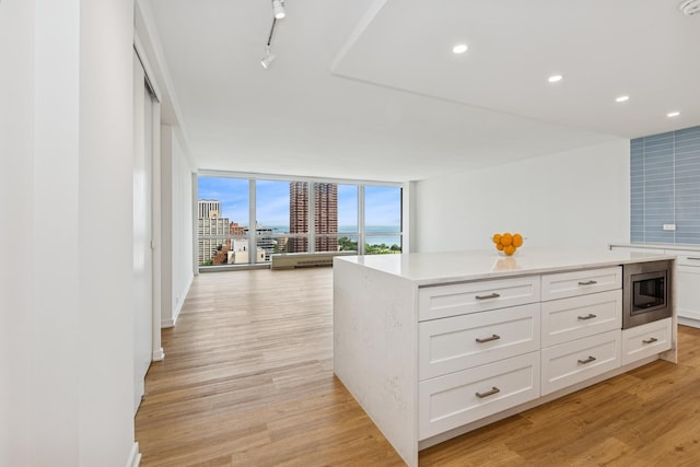 330 W Diversey Pkwy Unit 2306, Chicago, IL 60657 - kitchen featuring light wood-style flooring, stainless steel microwave, light countertops, floor to ceiling windows, and white cabinetry