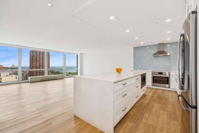 330 W Diversey Pkwy Unit 2306, Chicago, IL 60657 - kitchen with stainless steel appliances, wall chimney range hood, tasteful backsplash, light wood-style flooring, and recessed lighting