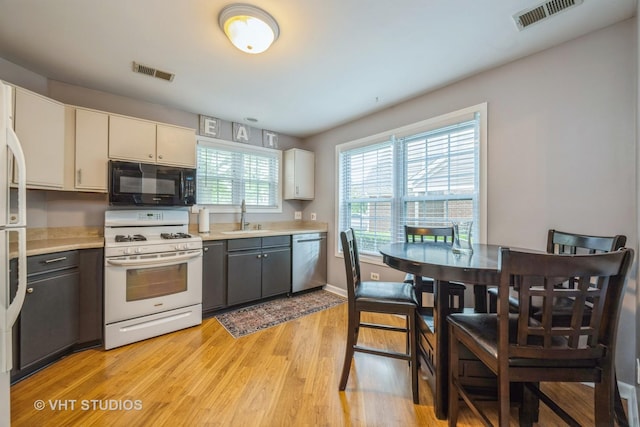285 Sheffield Dr, Schaumburg, IL 60194 - kitchen featuring white range with gas cooktop, black microwave, stainless steel dishwasher, light wood-style flooring, and light countertops