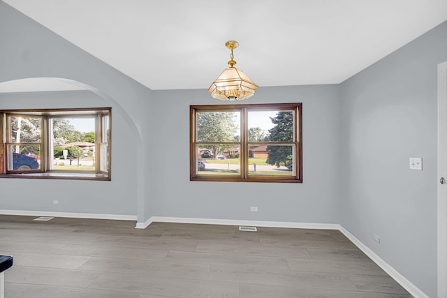 26W278 Harrison Ave, Winfield, IL 60190 - empty room featuring arched walkways, plenty of natural light, and wood finished floors