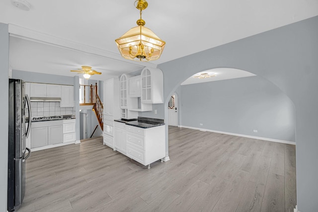 26W278 Harrison Ave, Winfield, IL 60190 - kitchen featuring freestanding refrigerator, arched walkways, dark countertops, light wood-style flooring, and white cabinetry