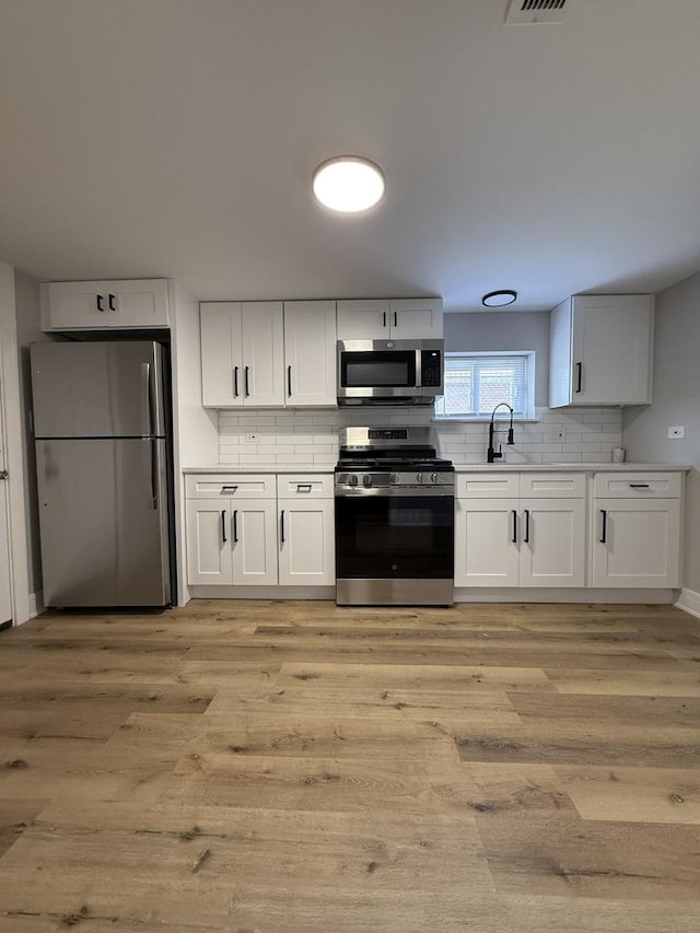 1400 W 73rd Pl, Chicago, IL 60636 - kitchen with stainless steel appliances, backsplash, white cabinets, light wood-type flooring, and light countertops