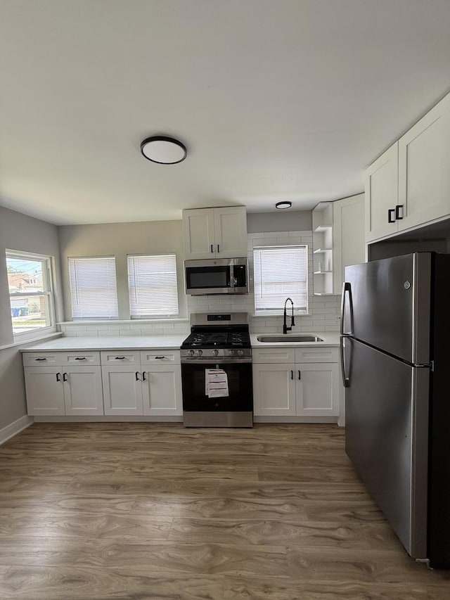 1400 W 73rd Pl, Chicago, IL 60636 - kitchen featuring appliances with stainless steel finishes, tasteful backsplash, white cabinets, and wood finished floors