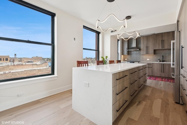 1261 N Paulina Ave Unit 6, Chicago, IL 60622 - kitchen featuring modern cabinets, wall chimney range hood, tasteful backsplash, light wood-style flooring, and a kitchen island