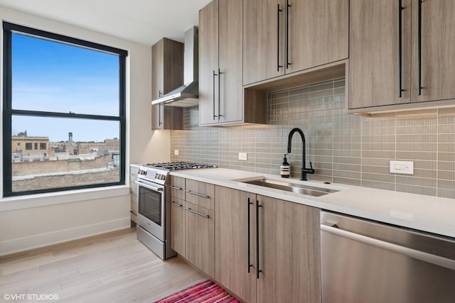 1261 N Paulina Ave Unit 6, Chicago, IL 60622 - kitchen featuring stainless steel appliances, wall chimney exhaust hood, light wood-style flooring, light countertops, and backsplash