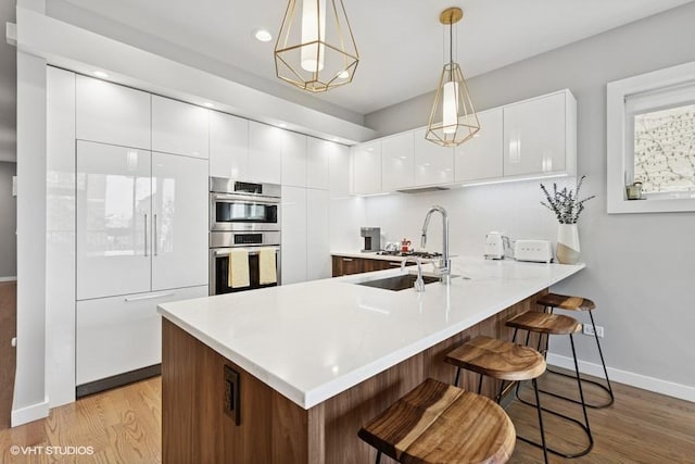 2237 N Hoyne Ave Unit 3S, Chicago, IL 60647 - kitchen featuring double oven, modern cabinets, a peninsula, a kitchen bar, and white cabinets