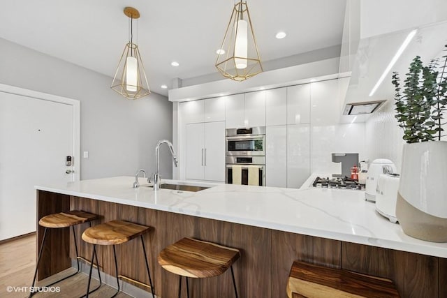 2237 N Hoyne Ave Unit 3S, Chicago, IL 60647 - kitchen with a peninsula, white cabinets, modern cabinets, stainless steel appliances, and decorative light fixtures