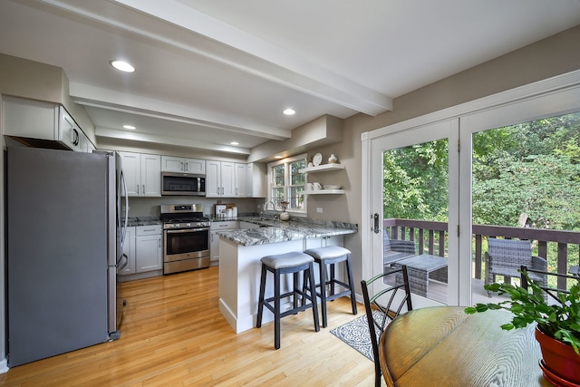 74 White Oak Cir, Saint Charles, IL 60174 - kitchen with stainless steel appliances, a peninsula, beamed ceiling, light stone counters, and light wood-style floors