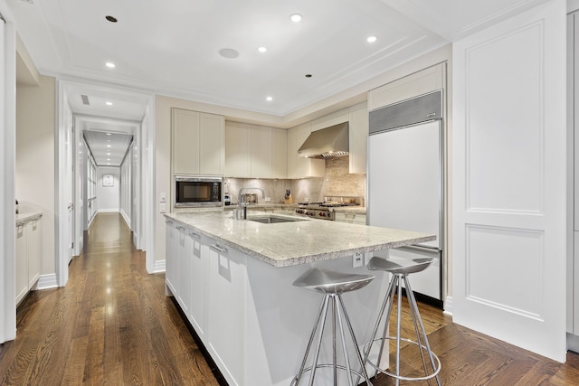 159 E Walton Pl Unit 5C, Chicago, IL 60611 - kitchen featuring built in appliances, wall chimney range hood, tasteful backsplash, a center island with sink, and dark wood-style flooring