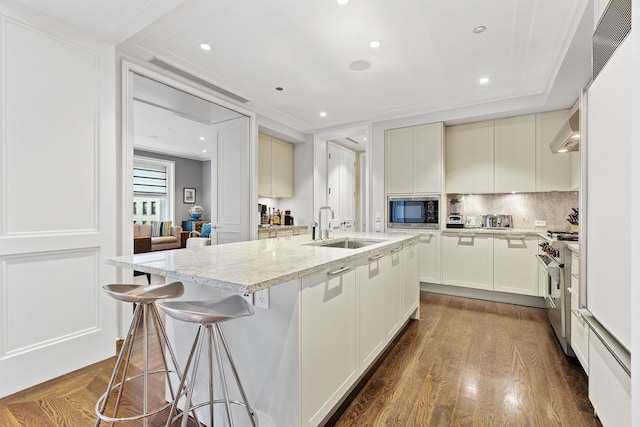 159 E Walton Pl Unit 5C, Chicago, IL 60611 - kitchen with stainless steel appliances, backsplash, wall chimney range hood, light stone countertops, and a breakfast bar