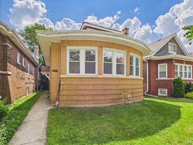 8015 S Paxton Ave, Chicago, IL 60617 - view of front of home with brick siding, a front yard, and a chimney