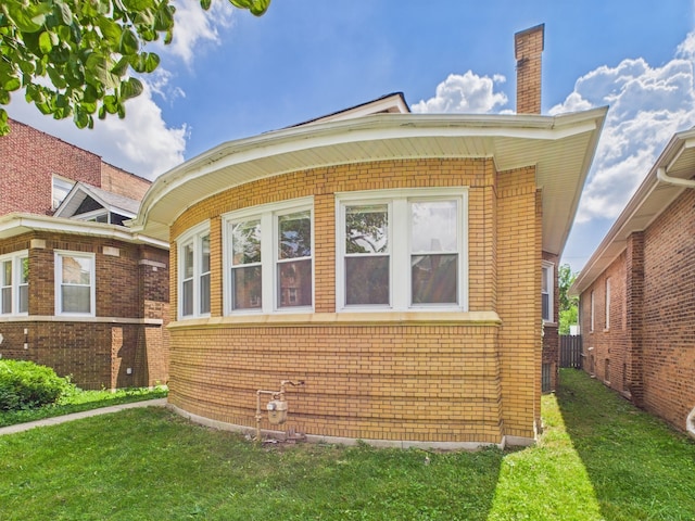 8015 S Paxton Ave, Chicago, IL 60617 - view of property exterior featuring brick siding, a lawn, and a chimney
