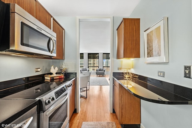 260 E Chestnut St Unit 3303, Chicago, IL 60611 - kitchen featuring stainless steel appliances, brown cabinetry, light wood-type flooring, dark countertops, and modern cabinets