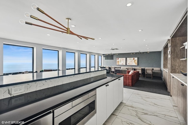 260 E Chestnut St Unit 3303, Chicago, IL 60611 - kitchen featuring light marble finish flooring, white cabinetry, stainless steel microwave, recessed lighting, and dark countertops
