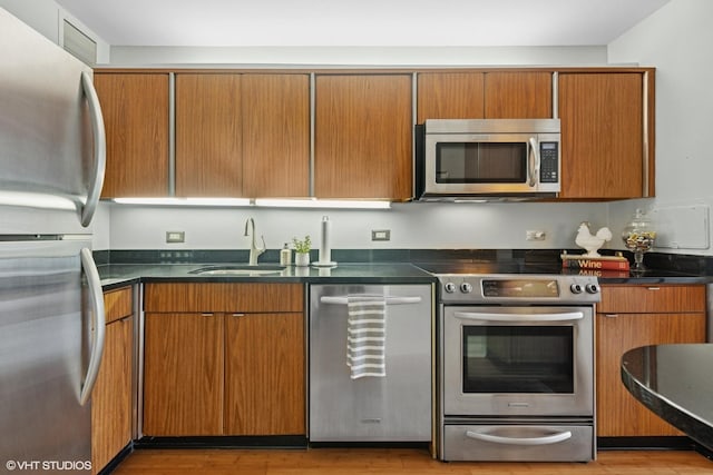 260 E Chestnut St Unit 3303, Chicago, IL 60611 - kitchen featuring appliances with stainless steel finishes, dark countertops, light wood finished floors, and brown cabinetry