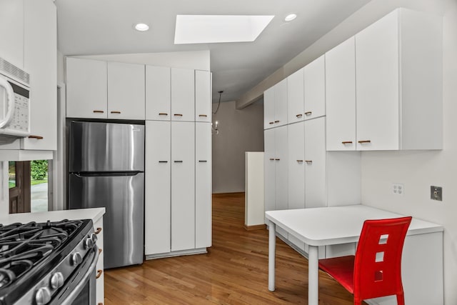 806 Lawler Ave, Wilmette, IL 60091 - kitchen featuring appliances with stainless steel finishes, a skylight, light wood-style flooring, light countertops, and white cabinets