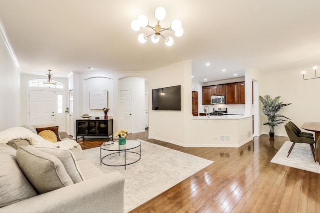 2302 Sandy Creek Dr, Algonquin, IL 60102 - living room featuring a chandelier, dark wood finished floors, arched walkways, recessed lighting, and crown molding
