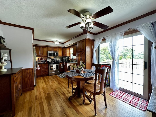 6119 Little Galilee Rd, Clinton, IL 61727 - dining area with light wood-style floors, a textured ceiling, crown molding, a ceiling fan, and a wainscoted wall