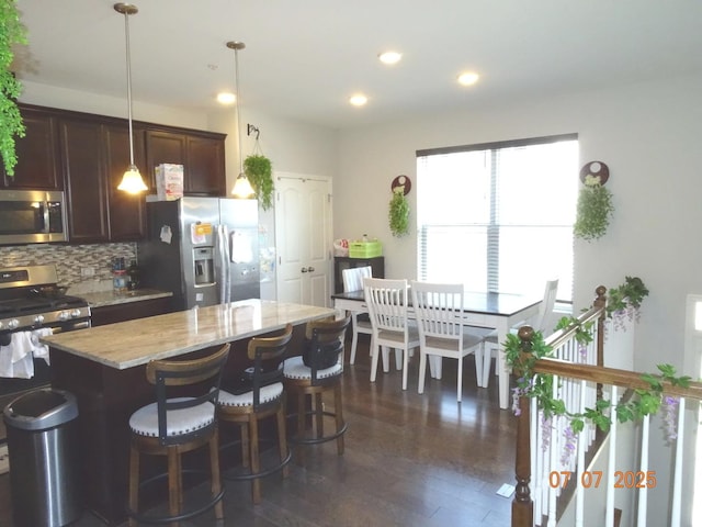 1108 Evergreen Ave, Des Plaines, IL 60016 - kitchen with appliances with stainless steel finishes, decorative backsplash, light stone counters, dark brown cabinets, and a kitchen island