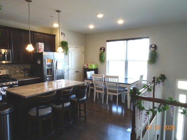 1108 Evergreen Ave, Des Plaines, IL 60016 - kitchen with stainless steel appliances, tasteful backsplash, dark brown cabinets, dark wood-style flooring, and hanging light fixtures