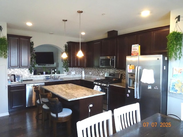 1108 Evergreen Ave, Des Plaines, IL 60016 - kitchen with stainless steel appliances, a kitchen island, dark brown cabinetry, tasteful backsplash, and pendant lighting