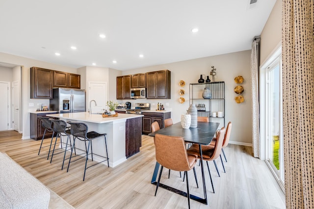 12124 Kelsey Dr, Huntley, IL 60142 - kitchen with stainless steel appliances, light wood-style floors, light countertops, a kitchen island with sink, and recessed lighting
