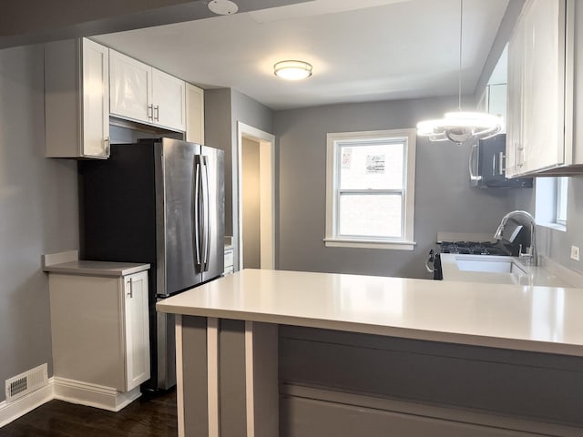 8517 S Wallace St, Chicago, IL 60620 - kitchen with stainless steel appliances, a peninsula, light countertops, white cabinetry, and dark wood-style floors