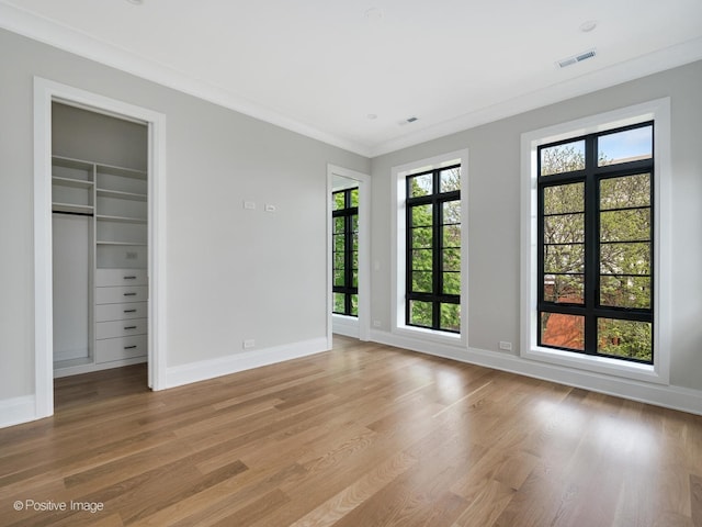 2832 N Racine Ave Unit 2W, Chicago, IL 60657 - unfurnished bedroom with light wood finished floors, multiple windows, a spacious closet, and ornamental molding
