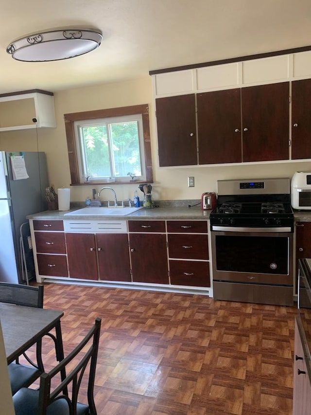 353 W Porter St, Oglesby, IL 61348 - kitchen with stainless steel gas range oven, freestanding refrigerator, white cabinetry, and dark brown cabinetry