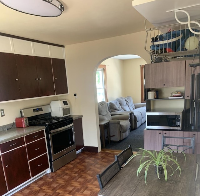 353 W Porter St, Oglesby, IL 61348 - kitchen featuring appliances with stainless steel finishes, arched walkways, dark brown cabinetry, open floor plan, and white cabinetry