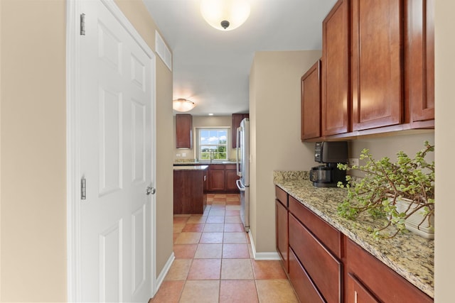 1644 Prairieview Blvd, Bolingbrook, IL 60490 - kitchen featuring freestanding refrigerator, light stone countertops, light tile patterned flooring, and brown cabinets