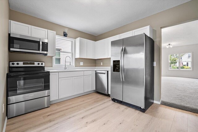 710 W Walnut St, Bloomington, IL 61701 - kitchen with appliances with stainless steel finishes, white cabinetry, light countertops, light wood-style flooring, and a textured ceiling