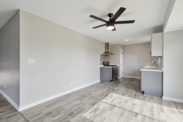 113 New Brunswick Ln, Poplar Grove, IL 61065 - kitchen with gas range, wall chimney range hood, light wood finished floors, light countertops, and ceiling fan