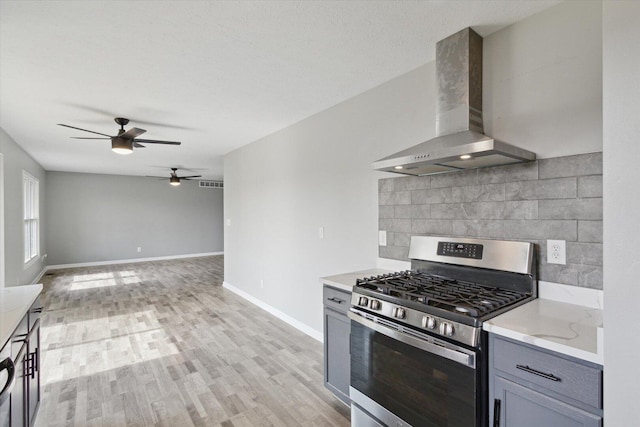 113 New Brunswick Ln, Poplar Grove, IL 61065 - kitchen featuring stainless steel gas stove, wall chimney exhaust hood, a ceiling fan, gray cabinetry, and backsplash