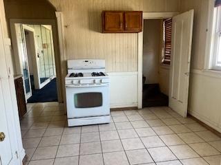 401 23rd Ave, Bellwood, IL 60104 - kitchen featuring white gas range, brown cabinets, and light tile patterned flooring