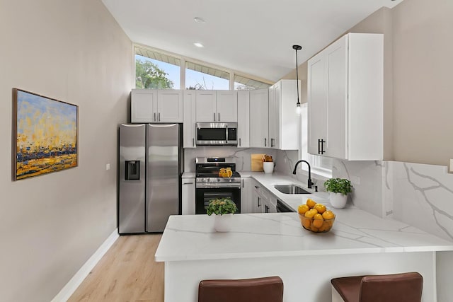 15224 Oak St, Dolton, IL 60419 - kitchen with appliances with stainless steel finishes, a peninsula, light wood finished floors, a breakfast bar, and hanging light fixtures