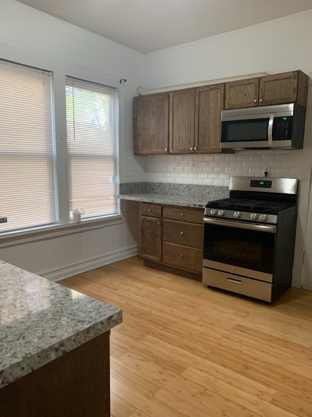 3255 N Kenneth Ave, Chicago, IL 60641 - kitchen with stainless steel appliances, light wood-type flooring, tasteful backsplash, and dark brown cabinets