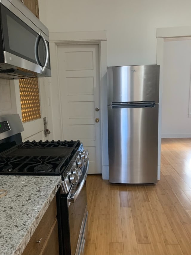3255 N Kenneth Ave, Chicago, IL 60641 - kitchen with appliances with stainless steel finishes, light wood finished floors, light stone counters, and decorative backsplash