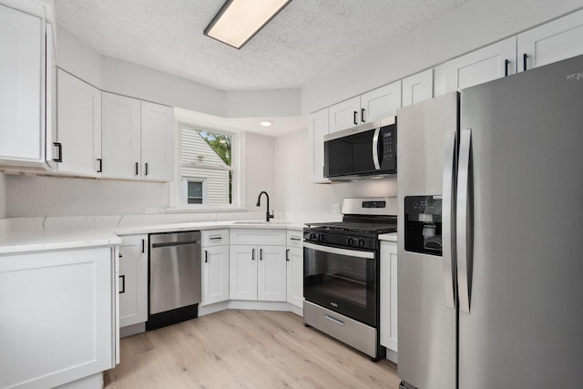 1225 Highridge Pkwy, Westchester, IL 60154 - kitchen with appliances with stainless steel finishes, light wood-style flooring, white cabinetry, a textured ceiling, and recessed lighting