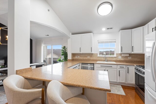 2599 Oak Dr Unit 2599, West Dundee, IL 60118 - kitchen with appliances with stainless steel finishes, a peninsula, a breakfast bar, healthy amount of natural light, and vaulted ceiling