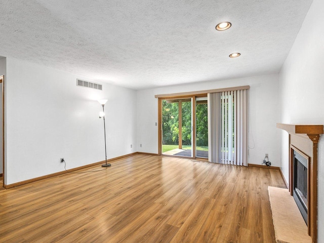 4176 Tumbleweed Trl Unit 0, Loves Park, IL 61111 - unfurnished living room with a textured ceiling, a fireplace with flush hearth, light wood-style floors, and recessed lighting
