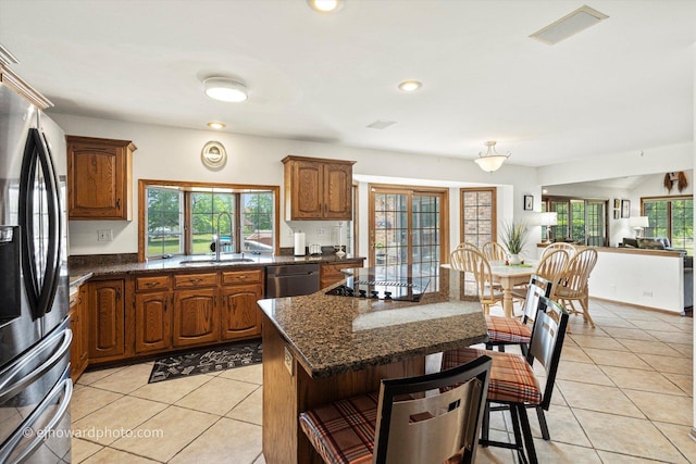 3250 Platte Trl, Olympia Fields, IL 60461 - kitchen with appliances with stainless steel finishes, light tile patterned floors, a breakfast bar, brown cabinets, and a kitchen island