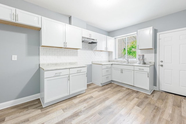 1310 E 72nd St, Chicago, IL 60619 - kitchen featuring under cabinet range hood, backsplash, light wood-type flooring, white cabinets, and light countertops
